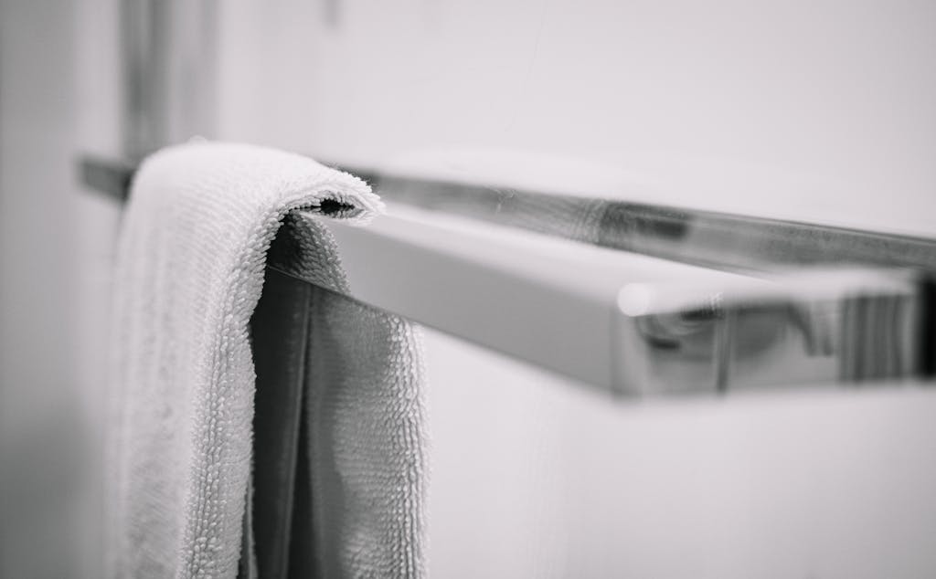 A clean white towel hangs on a shiny chrome towel rack, creating a minimalist and modern bathroom aesthetic.