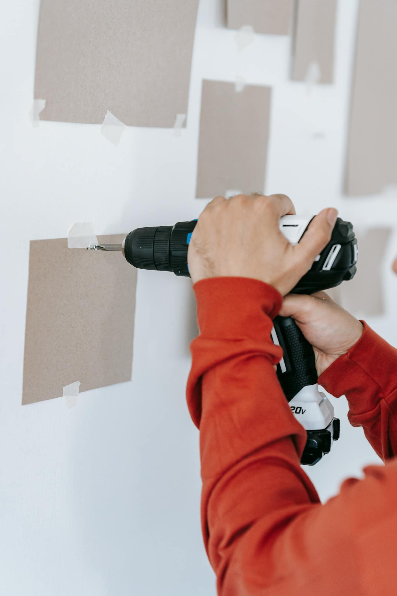 Close-up of hands using a drill on wall in home improvement setting.