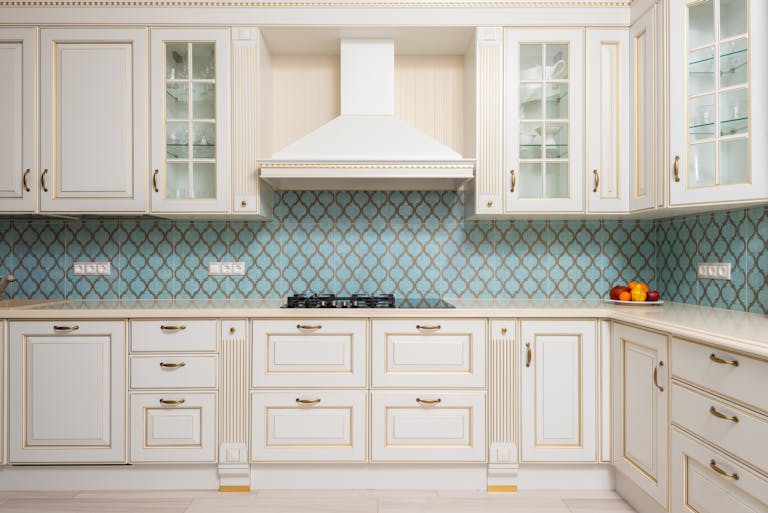 Interior of light modern kitchen with wooden white cabinets and blue tile backsplash with classic hood